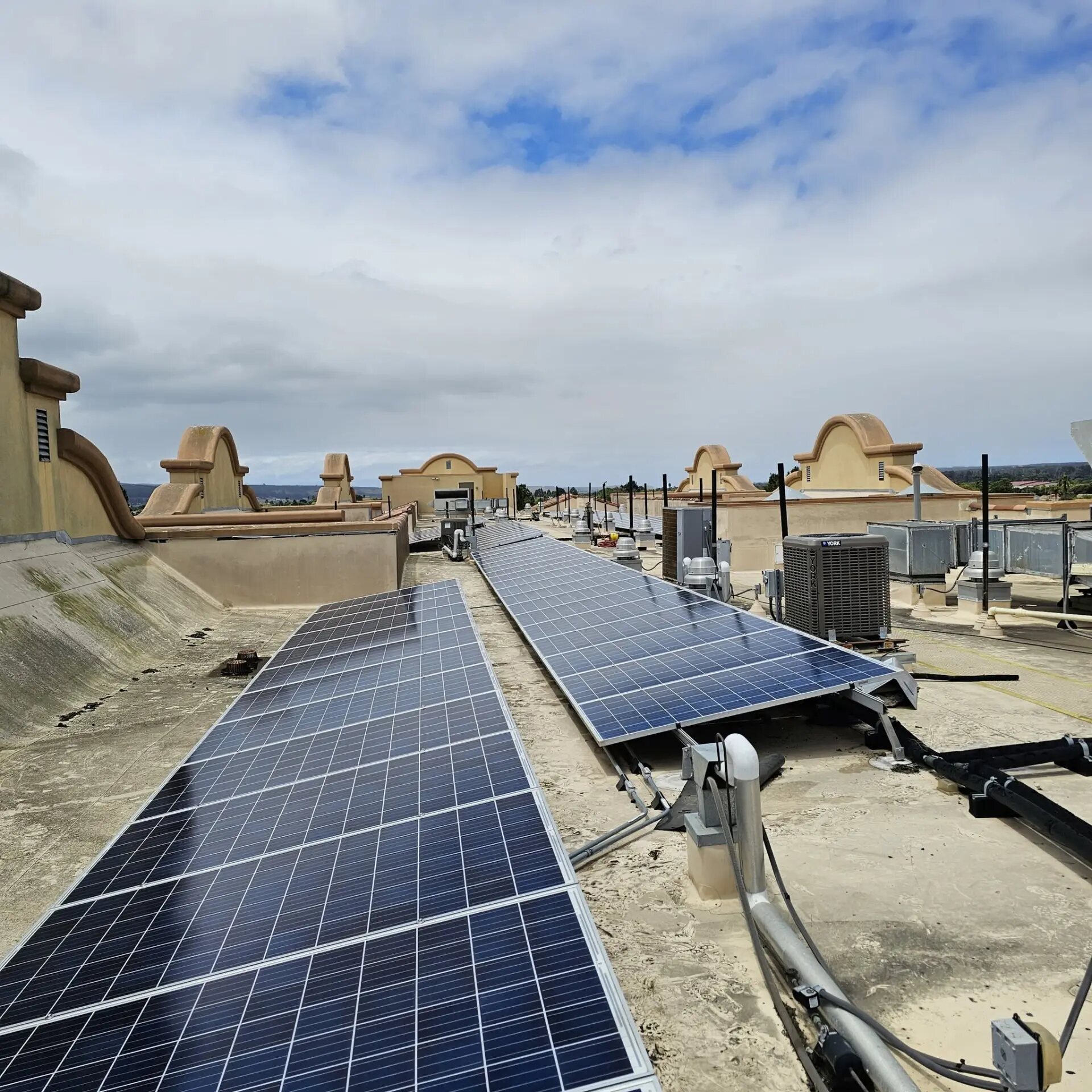 Rooftop solar panel array on a California commercial building under a bright sky